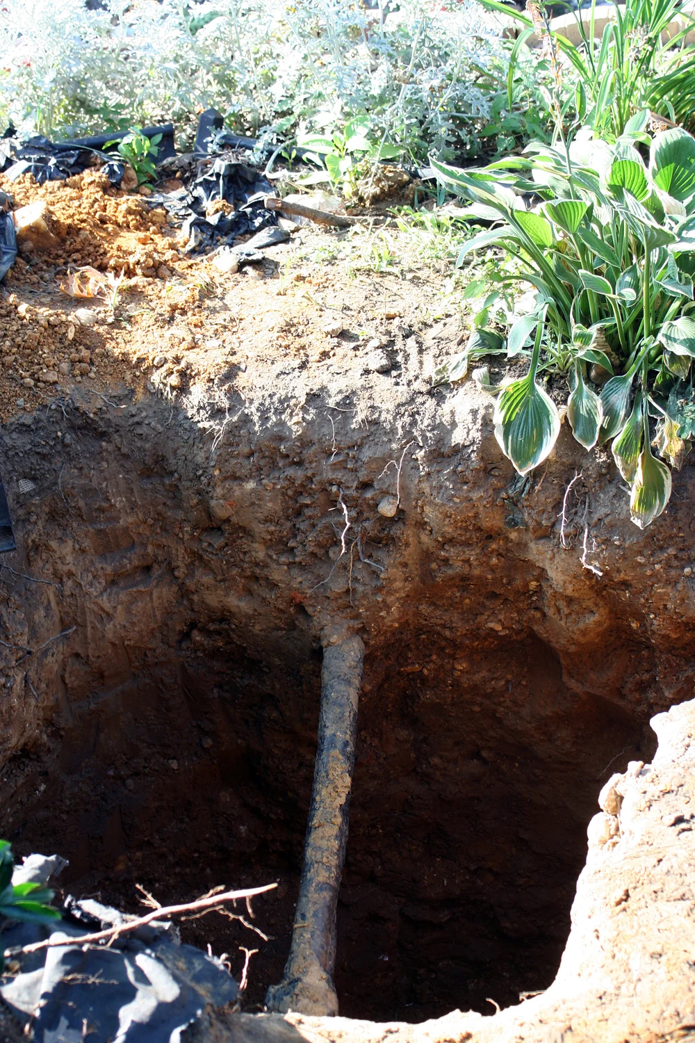 An excavated trench in front of a Washington, D.C. home exposing an old lead water service line during a DC Water replacement project.