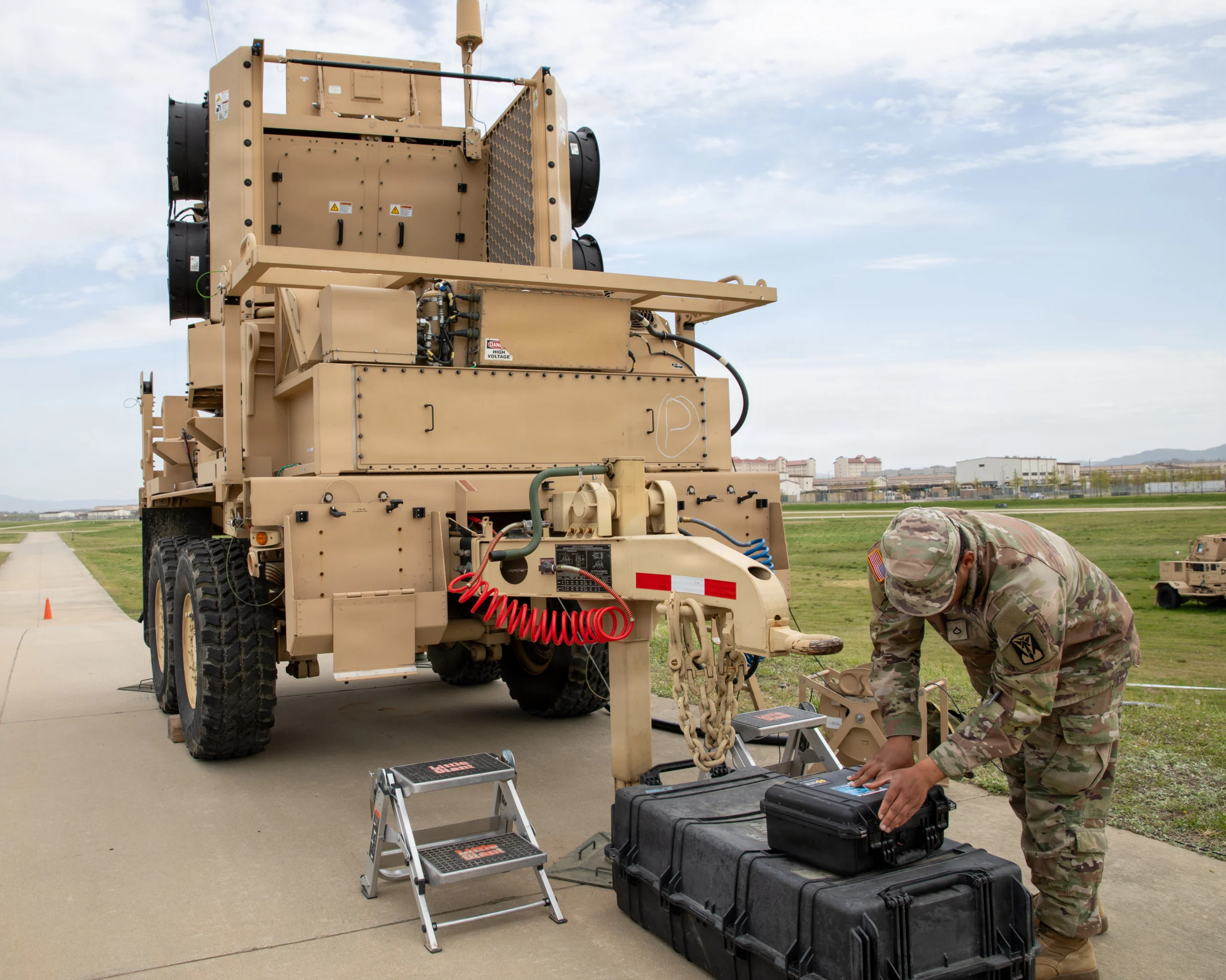 A U.S. Army soldier setting up equipment cases beside a trailer mounted Sentinel A4 radar