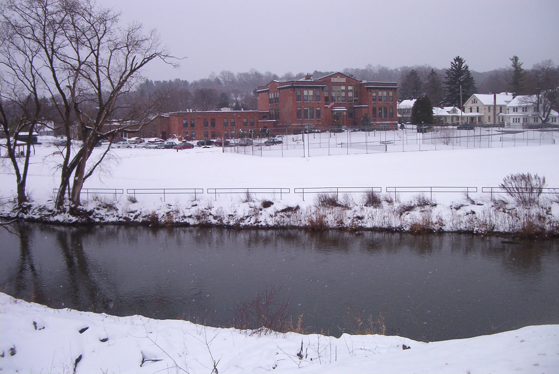 Nine Mile Creek in Camillus, New York, with a large brick school building beyond the water