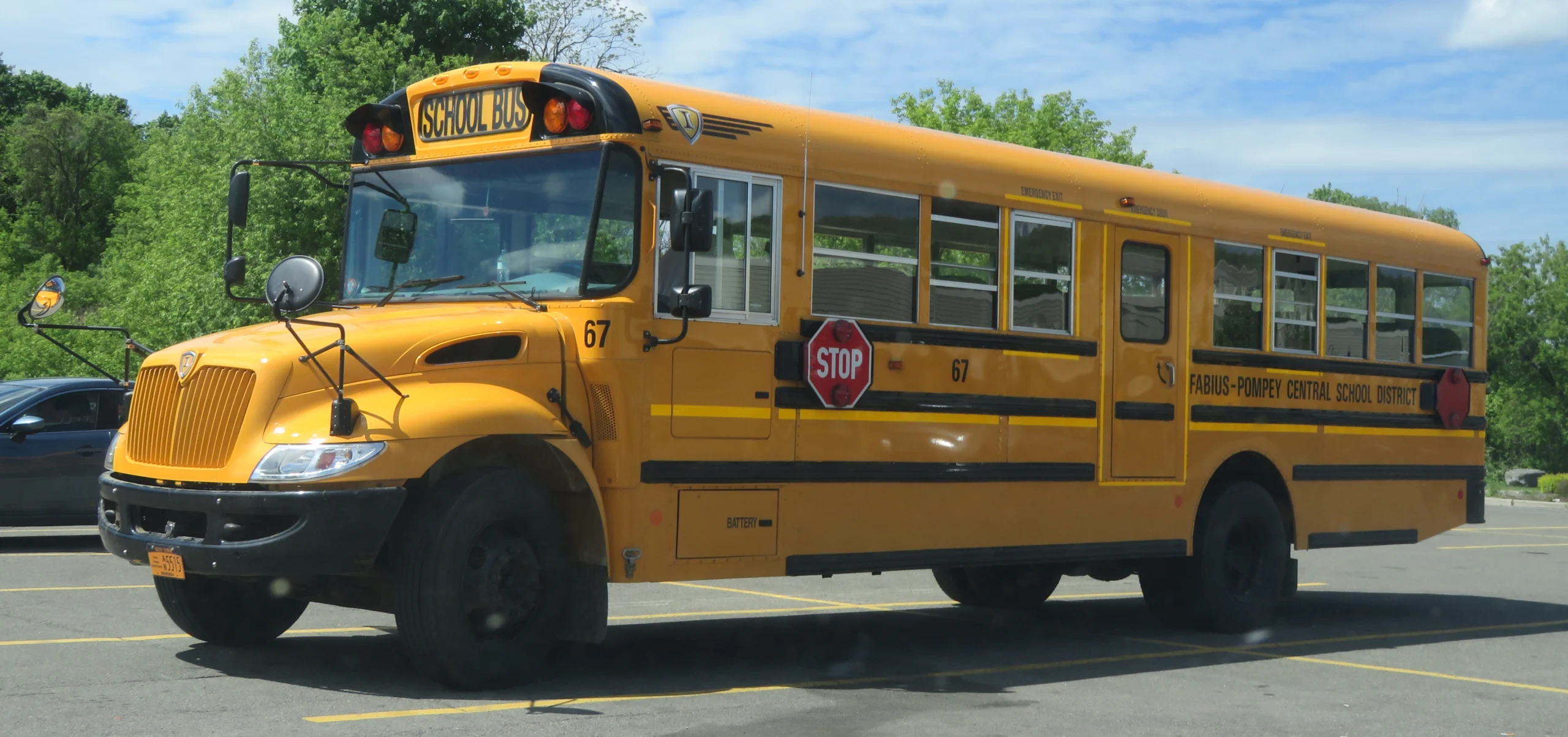 A yellow Fabius-Pompey Central School District bus numbered 67 in a parking lot