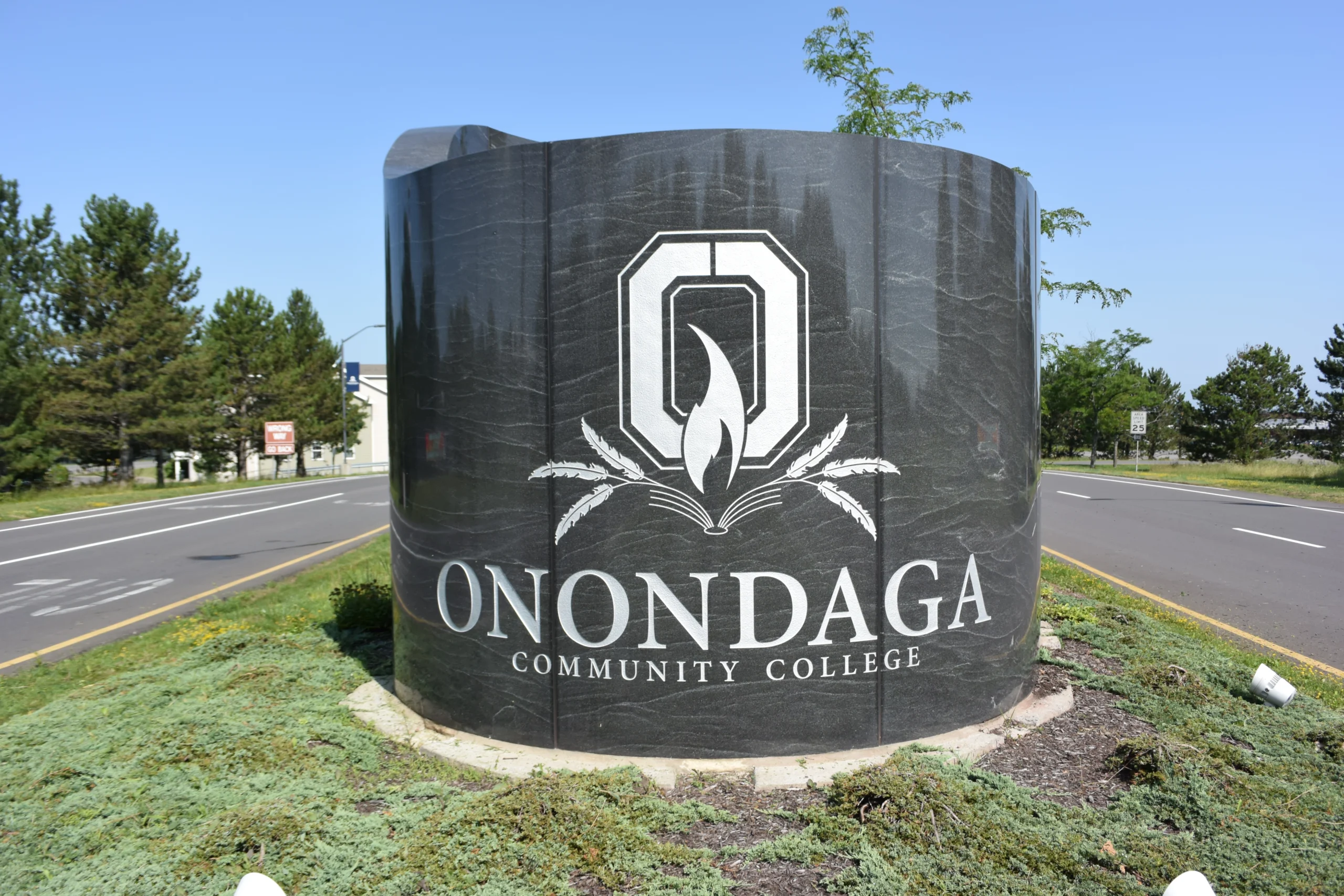 The stone Onondaga Community College entrance sign beside a road on Onondaga Hill
