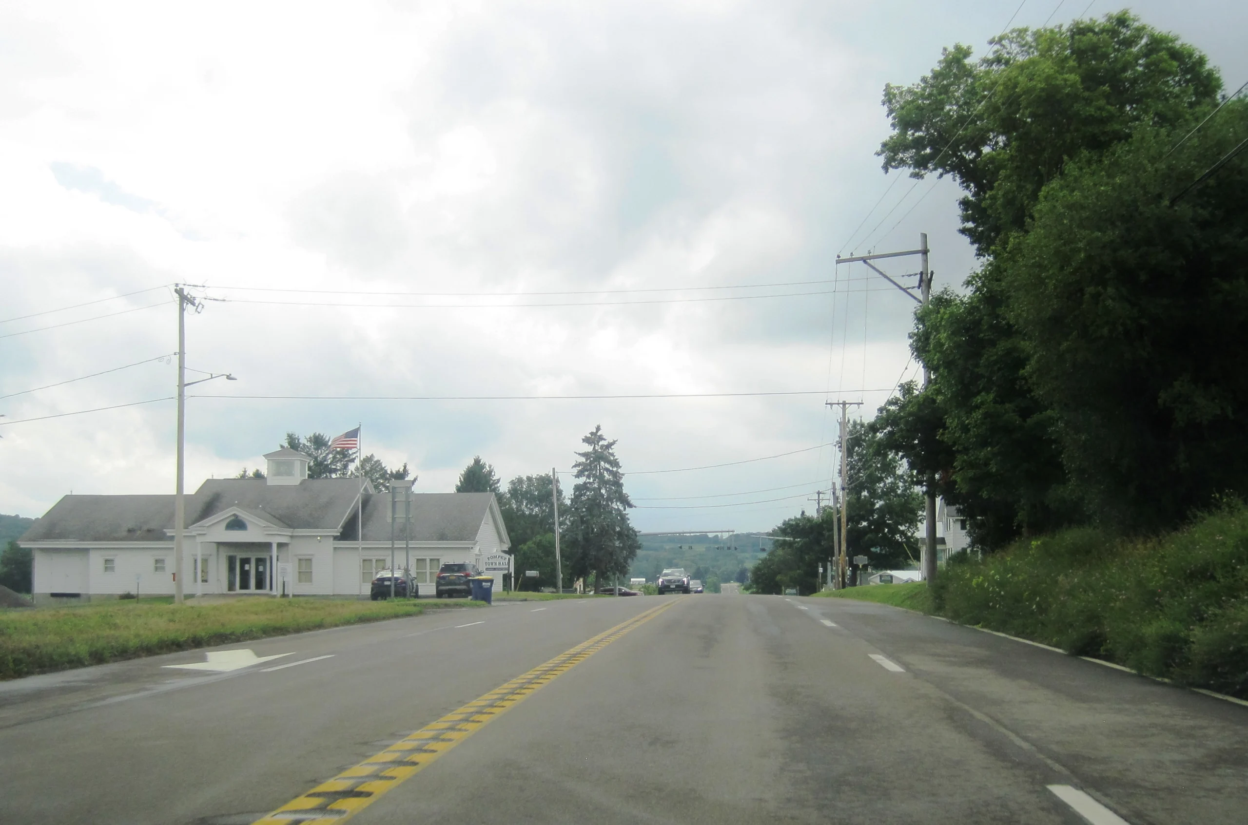 The white Pompey Town Hall building with its cupola and flagpole along U.S. Route 20