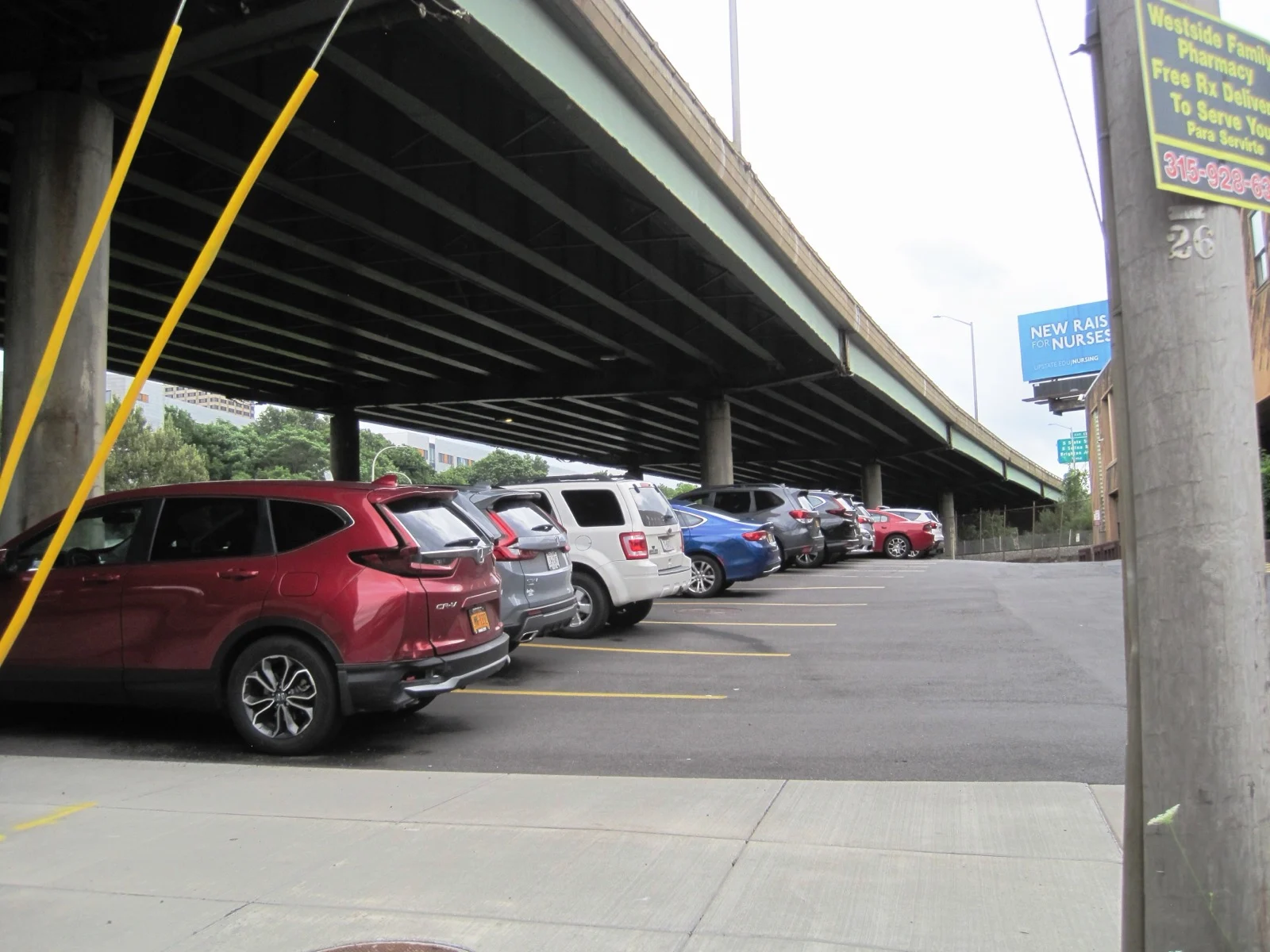 The underside of the elevated Interstate 81 viaduct in Syracuse with cars parked beneath it