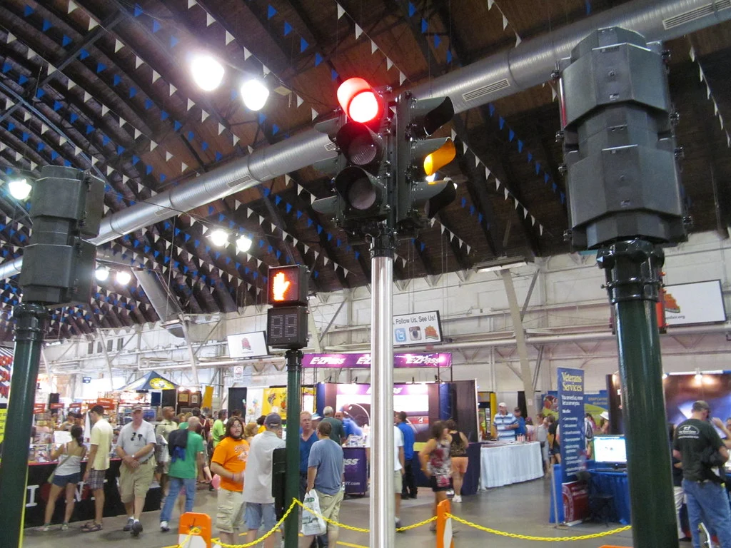 Crowds walking among vendor booths inside an exhibit building at the New York State Fair