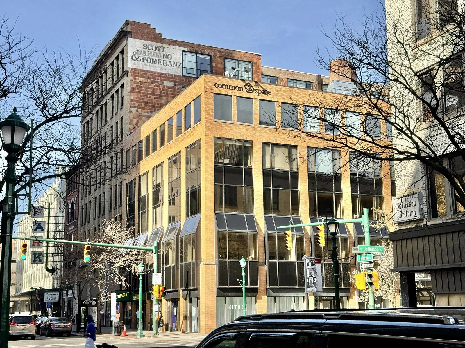 A downtown Syracuse street corner with ground floor storefronts and traffic signals